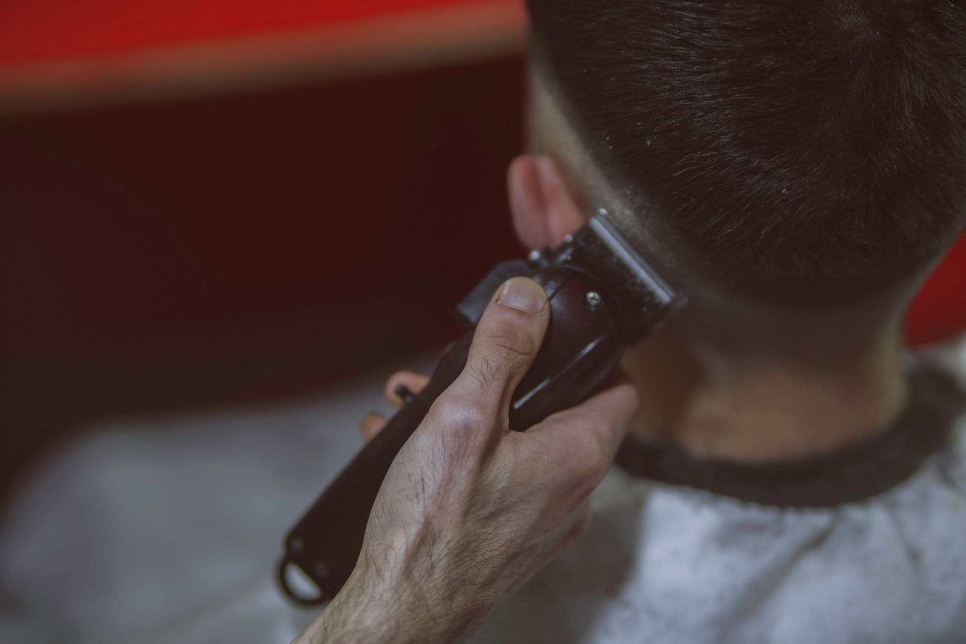 Primer plano de un barbero haciendo un degradado con la máquina