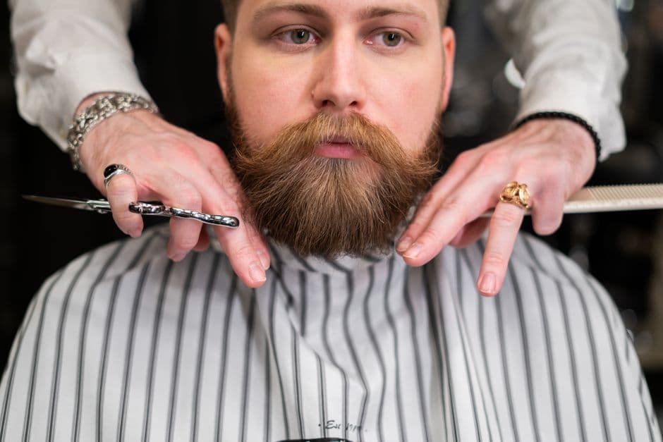 Hombre con barba recibiendo un delineado de precisión en la barbería.