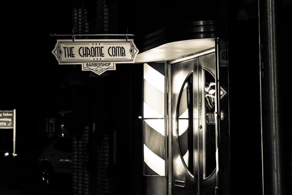 Vintage art deco barbershop entrance captured in monochrome at night.