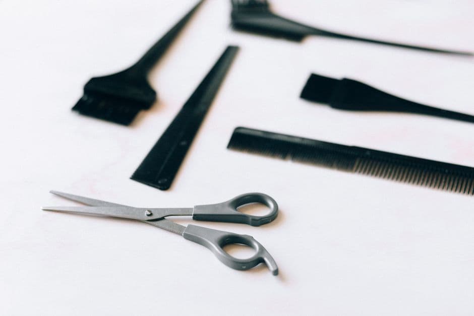 A collection of essential hairdressing tools including scissors and combs on a white surface.